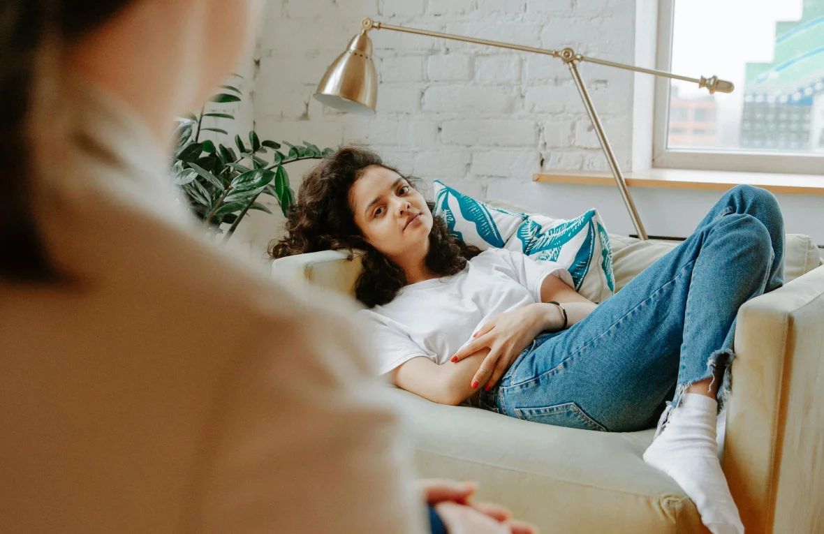 A young woman lying on a couch with a therapist visible in the foreground, symbolizing Internal Family Systems (IFS) Therapy in Tempe AZ.